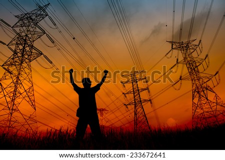 Man silhouette in the sunset sky with hand rise up at the high-voltage tower