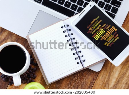 Online Banking word cloud arrangement concept on smartphone screen. Notebook,smartphone,book and a cup of coffee on wooden table.