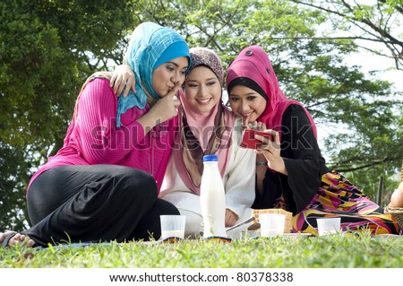muslim girls having fun at park. they might be using 3g technology with their friend by mobile