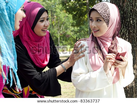 young muslim woman in head scarf having fun when meeting at park with friends