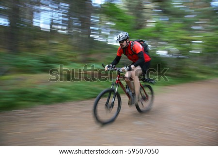 A mountainbiker in a forest in aviemore, scotland. Face is sharp, rest has got motion blur.