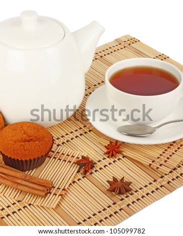 Teapot and cup of tea with spice and muffins on wooden mat, food photo