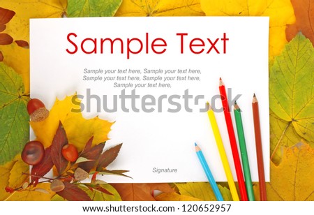 Colorful frame of fallen autumn leaves with white paper sheet and color pencils & text