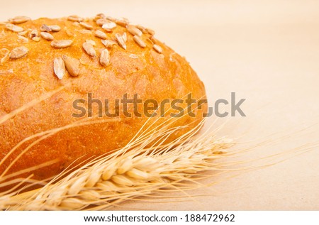 Loaf of bread with seeds and spikelets of wheat, food photo