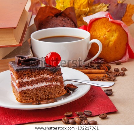 Chocolate cake and cup of coffee with books and autumn leaves