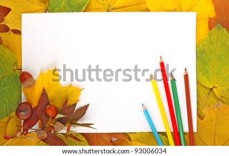 Colorful frame of fallen autumn leaves with white paper sheet and color pencils