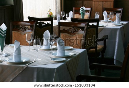 Restaurant dinner table place setting: napkin, wineglass, plate and flowers