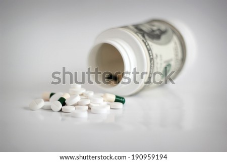 Money with pills, high costs of expensive medication concept. Shallow depth of field.