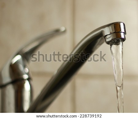 Water tap with flowing water. Selective focus, shallow depth of field.