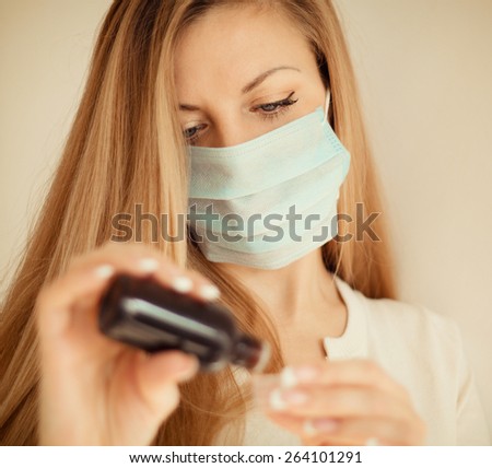 Woman in mask hand holding medicine health care syrup. Shallow depth of field.