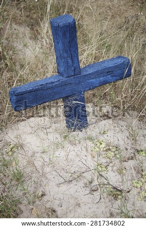 Old painted wooden cross on the grave of the rural cemetery