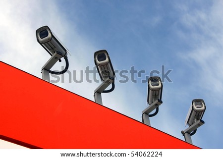 Four observation cameras on a red roof against the blue sky.