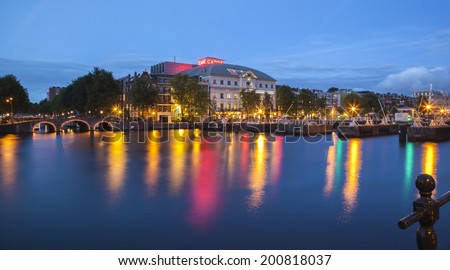AMSTERDAM, THE NETHERLANDS -  JUNE 20, 2014: Night view of the river Amstel looking towards theater 'Carre' with a piece of art in the river in Amsterdam, The Netherlands, on June 20, 2014