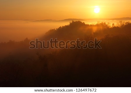 Early morning sunrise landscape with the sun beams playing over the slopes of the mountain.