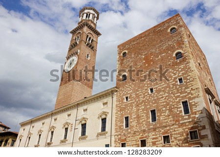 Torre dei Lamberti facade on piazza Erbe in Verona, Italy in a bright sunny day with some dramatic clouds at the background.
