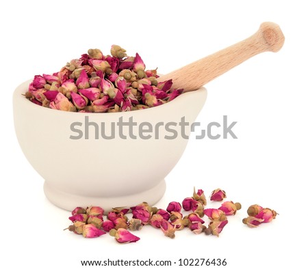 Rosebud flowers used in traditional chinese herbal medicine and the cosmetic industry in a stone mortar with pestle over white background.