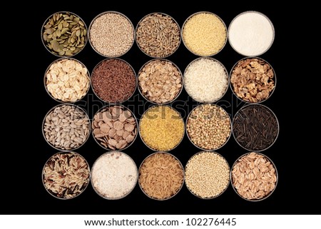 Large selection of cereal, seed and grain food in bowls over black background.