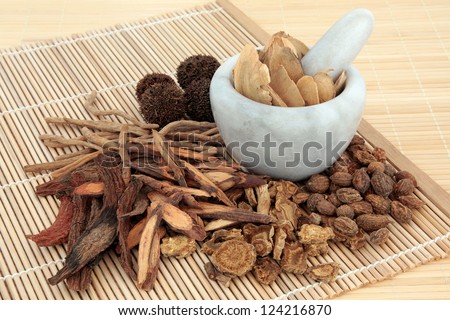 Chinese herbal medicine selection in a marble mortar with pestle and loose over bamboo mats.