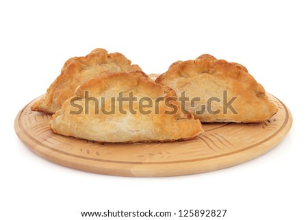 Cornish pasties on a beech wood board over white background.