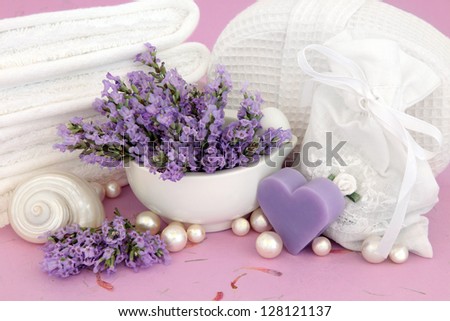 Lavender herb flower sprigs, soap, bag, shells, pearls and spa accessories over mottled pink background.