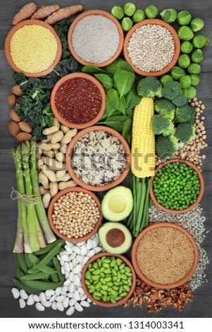 Healthy high protein super food with fresh vegetables,legumes, grains, seeds and nuts, health foods high in dietary fibre, vitamins and antioxidants. Top view on rustic wood background.