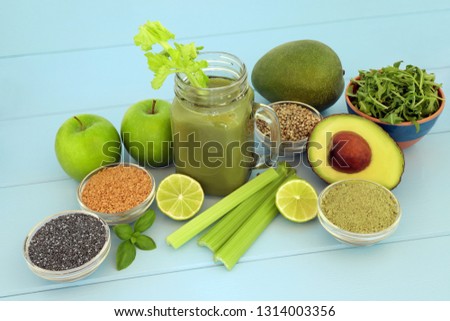 Health food diet smoothie drink with fresh fruit, vegetables, matcha powder, flax, chia and hemp  seed on blue wood background. High in omega 3, antioxidants, vitamins and dietary fibre.