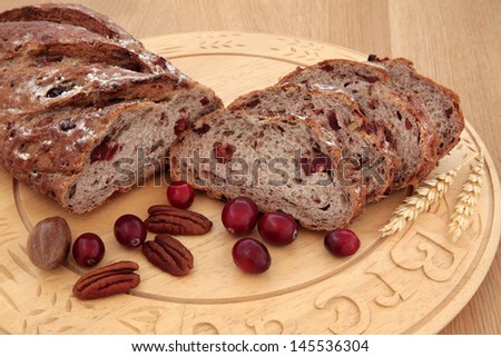 Cranberry and pecan bread on a beech wood bread board over oak background.