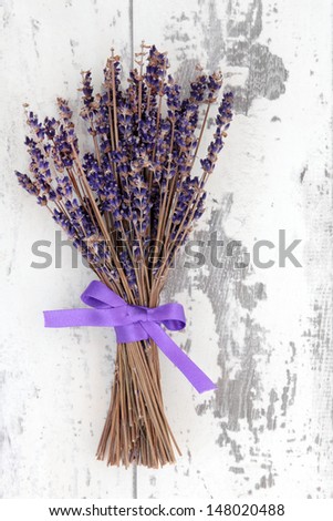 Dried lavender herb flowers tied in a bunch over distressed white wooden background.