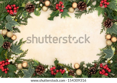 Christmas background border of natural holly, ivy, mistletoe and gold bauble decorations over old parchment.