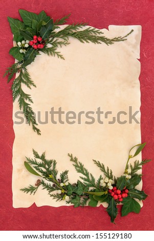 Christmas background border with holly, mistletoe, ivy and cedar leaf sprigs over old parchment and red mottled background.