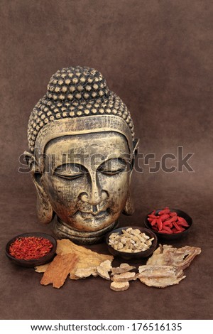 Chinese herbal medicine selection with buddha head over handmade lokta paper background.