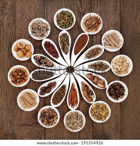 Large chinese herbal medicine selection in china bowls over old oak background.