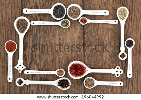 Measuring spoons with herb and spice food ingredients over old oak background.