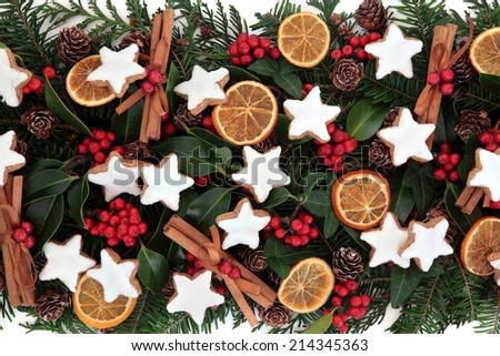 Christmas food background with gingerbread biscuits, dried fruit and spice and winter greenery.