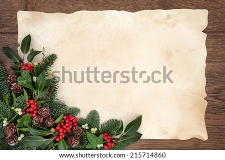 Christmas and winter background border with fir, holly, ivy, mistletoe and pine cones over old parchment paper and oak wood.
