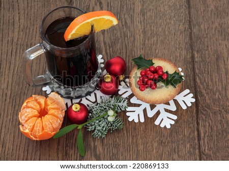 Christmas mulled wine with mince pie, red bauble decorations and winter flora over oak background.
