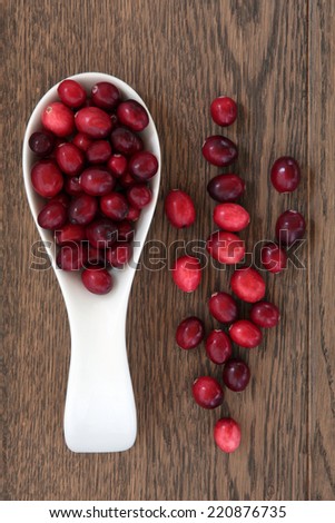 Cranberry fruit in a wooden spoon over oak wood background.