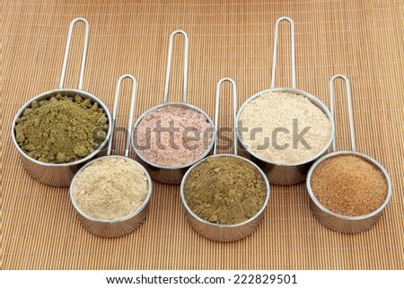 Protein and health supplement food powders in scoops. Hemp, ginseng, chocolate whey, ginkgo biloba, macca root and pomegranate left to right.