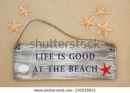 Life is good at the beach sign with starfish and cockle shell on sand background.