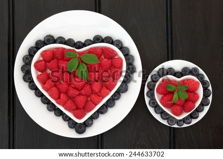Blueberry and strawberry super food fruit in heart shaped and round dishes with leaf sprigs.