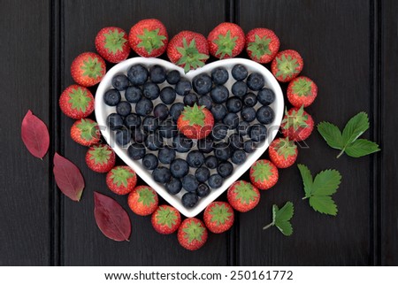 Blueberry and strawberry antioxidant fruit in a heart shaped dish with corresponding leaf sprigs.