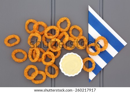 Onion ring snack food with mayo dip and striped napkin.