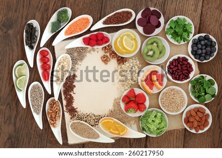 Diet detox super food selection in porcelain bowls on a speckled hemp paper notebook over oak wood background.