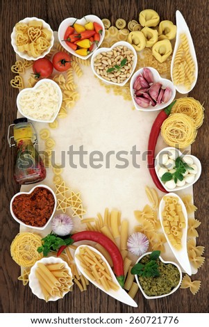 Italian pasta and food ingredients forming an abstract border over old parchment and oak wood background.