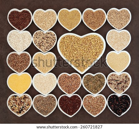 Grain and cereal food selection in heart shaped porcelain bowls over lokta paper background. Kamut khorasan wheat in large dish.