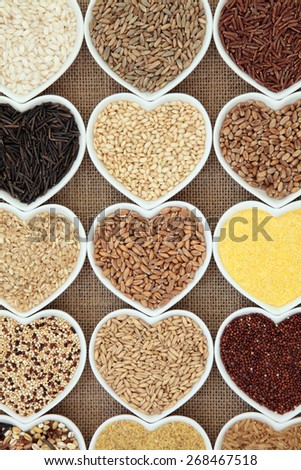 Grain and cereal food selection in heart shaped porcelain bowls over hessian background.
