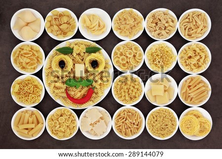 Abstract spaghetti and herb face  with large pasta food selection in round bowls over brown background.