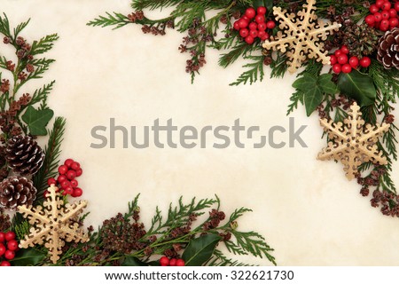Christmas background border with gold snowflake bauble decorations, holly, ivy and winter greenery over old parchment paper.
