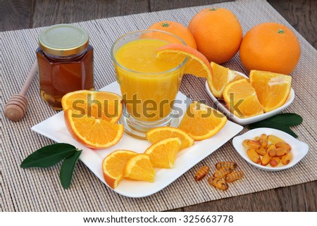 Health food for cold cure relief with freshly squeezed orange fruit juice, vitamin c tablets and honey on bamboo over oak background.