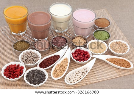Health and body building high protein super food with supplement powders with orange, chocolate whey, red maca and acai berry smoothies, fruit, grains, seeds, pulses and nuts over white background.